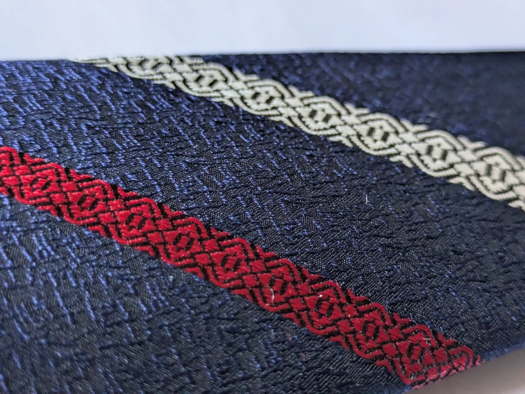 Close-up of navy Hakata-ori silk with red and pale Kenjo motifs