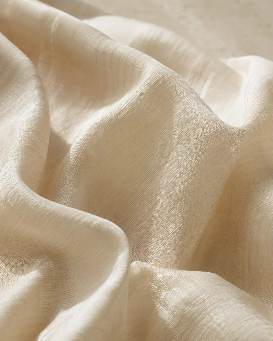 Close-up of softly folded ivory silk showing fine woven texture